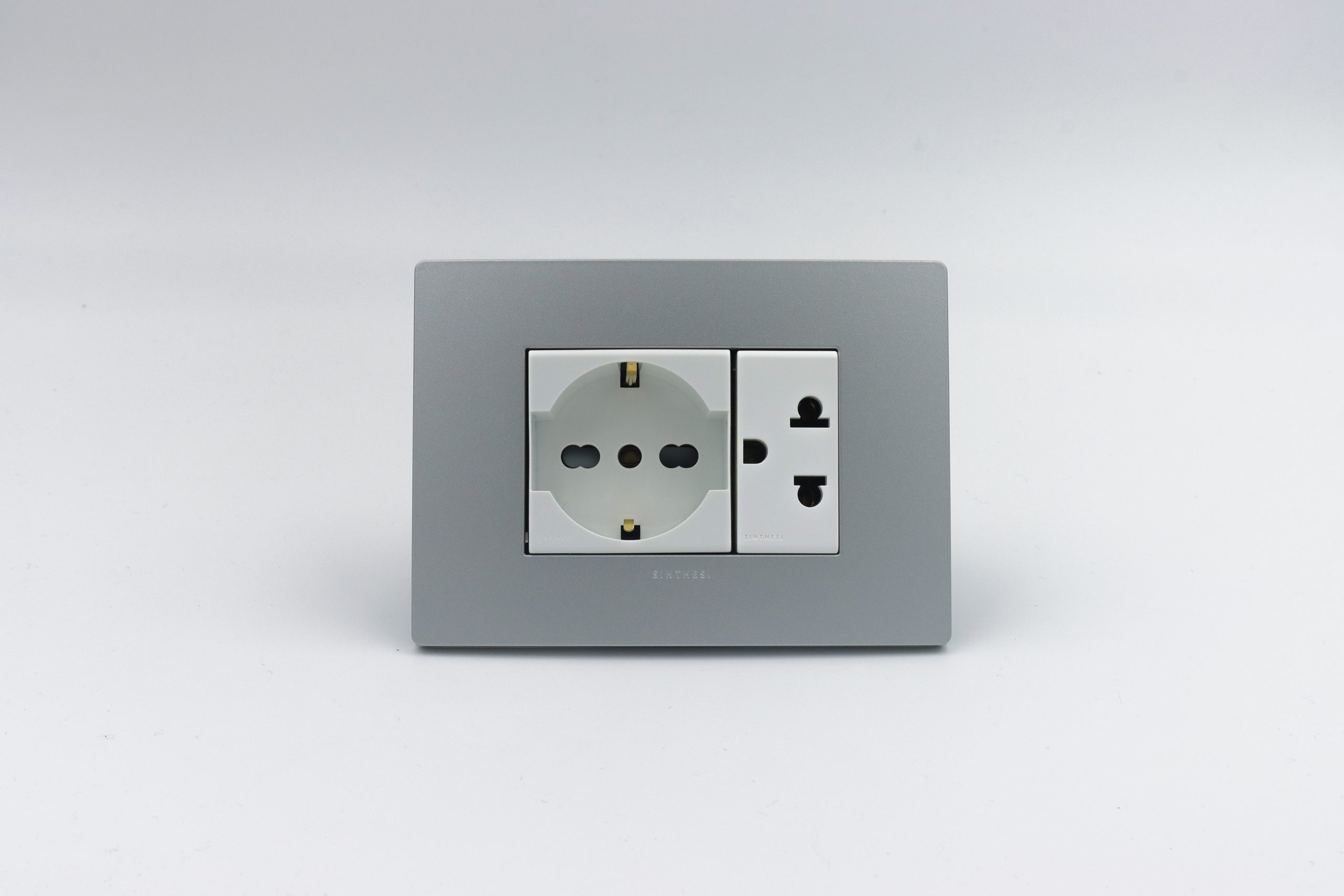 TOMACORRIENTE DOBLE (01 SCHUKO + 01 UNIVERSAL CON TIERRA) S33 PLACA PLATA Y DADOS S22 BLANCOS SINTHESI